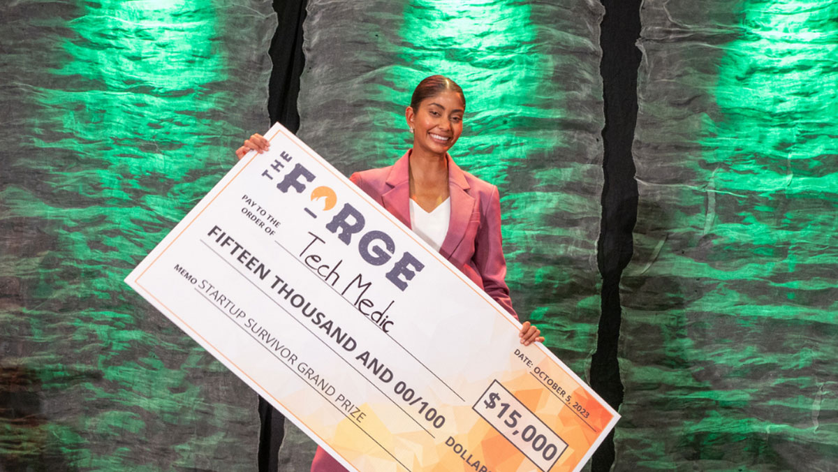 Shania Bhopa holds up a giant cheque for $15,000 that she won as Startup Survivor winner.