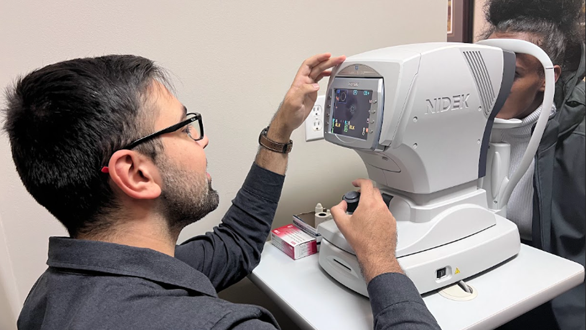 A medical learner, Amin Hatamnejad, performs an eye exam on a patient at the refugee vision screening clinic.