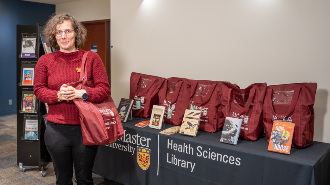 Laura Banfield stands in the Health Sciences Library beside a display of book club kits.