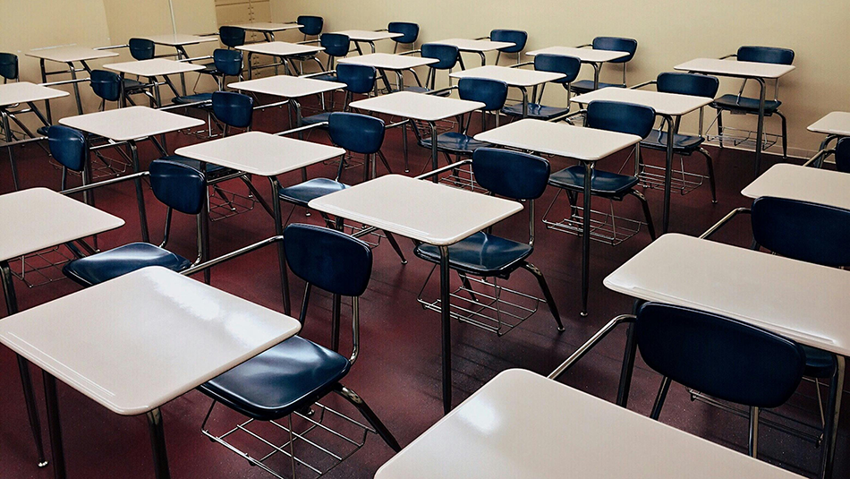 An empty classroom filled with desks can be seen in this image.