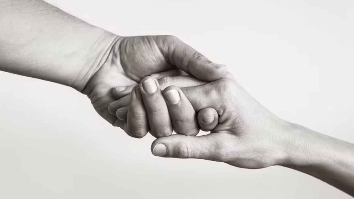 Black and white image of two hands reaching out and holding onto one another
