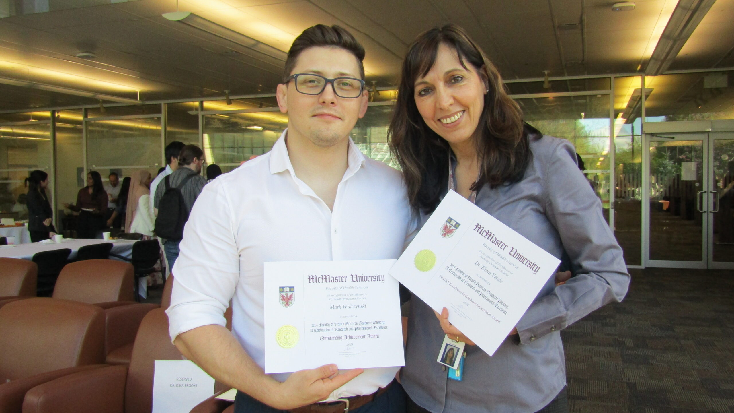 PhD student Mark Wulczynski and his supervisor Elena Verdu smile side-by-side holding certificates of their awards at the Graduate Plenary.