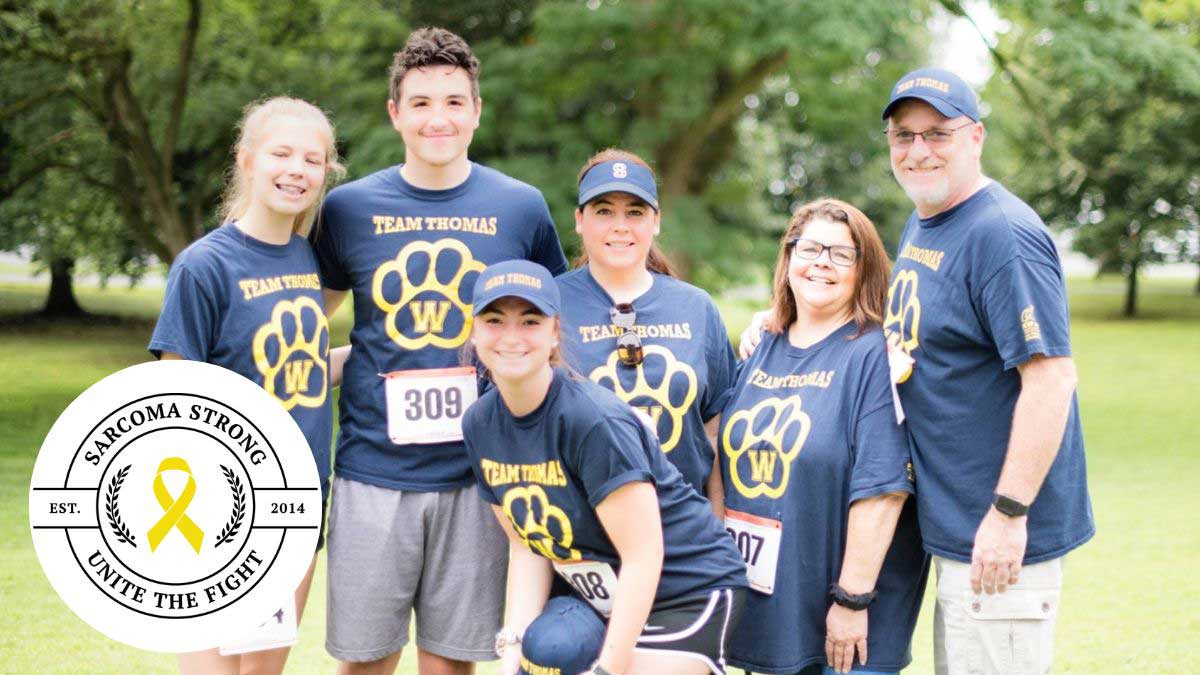 A team of Sarcoma Strong participants standing together and smiling at one of the previous 5K runs.