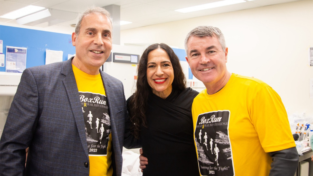 Three individuals standing side by side. The two people on the sides wear t-shirts with “Box Run” graphics, while the person in the centre is dressed in black.