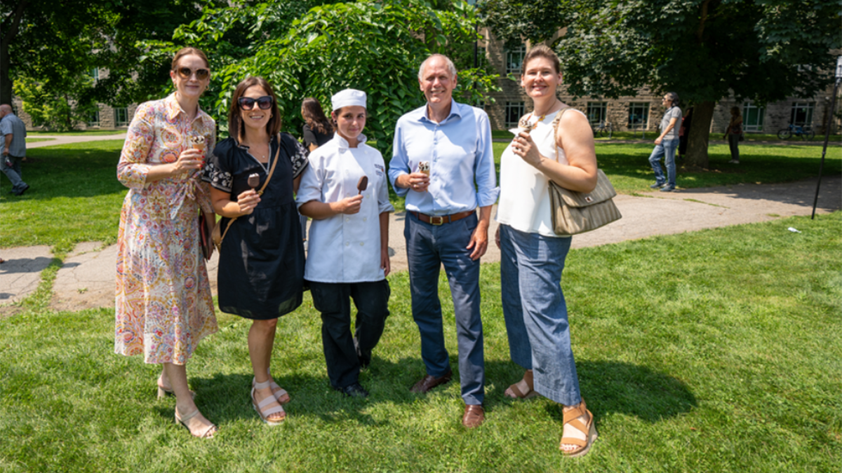 President Farrar and four staff members are holding ice cream and smiling on BSB field