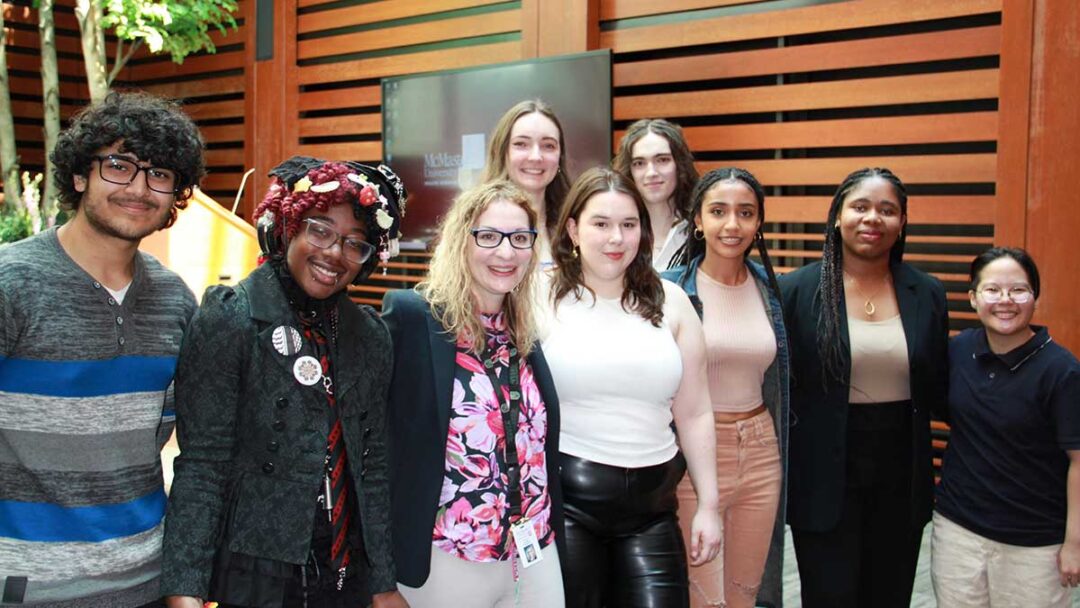 A diverse group of students pose together with Summer Scholars Program facilitator Monica De Paoli after completing their studies in the program.