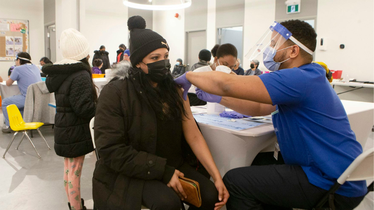 A person in winter clothing and a covid mask gets a vaccination at a covid vaccination clinic.