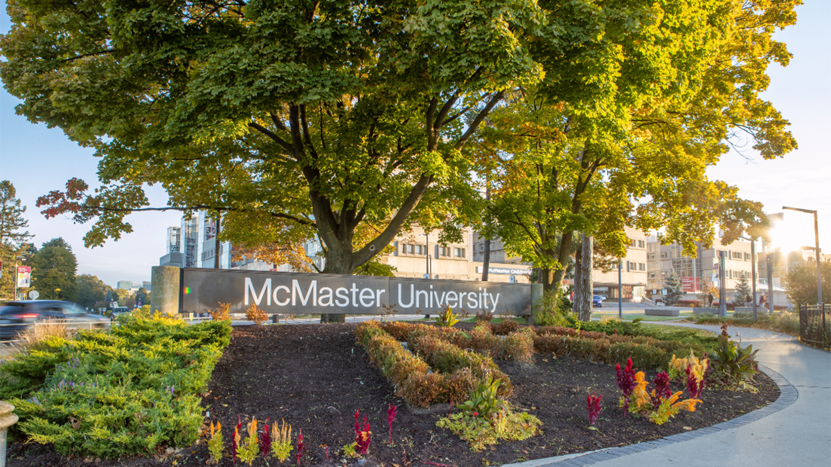 The McMaster University sign at the entrance to campus, on a sunlit fall day.