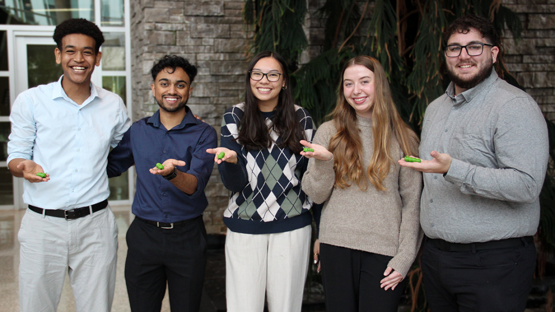 Students posed together, holding caterpillar-shaped props that are used to make needles appear less threatening.