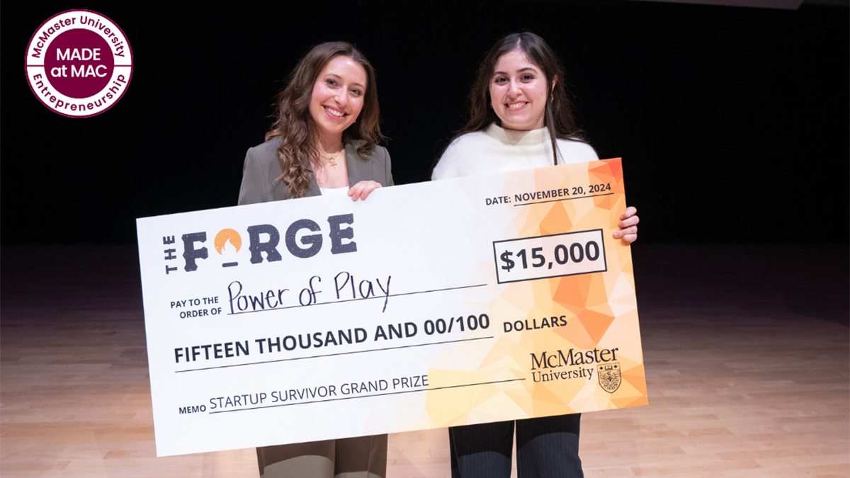 Two people smile, holding a large cheque for the Forge's $15,000 Startup Survivor Grand Prize.