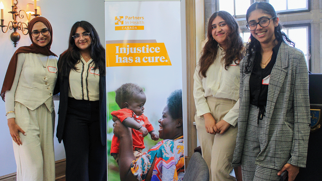 Students with McMaster University stand in front of a banner for the Partner in Health policy competition.