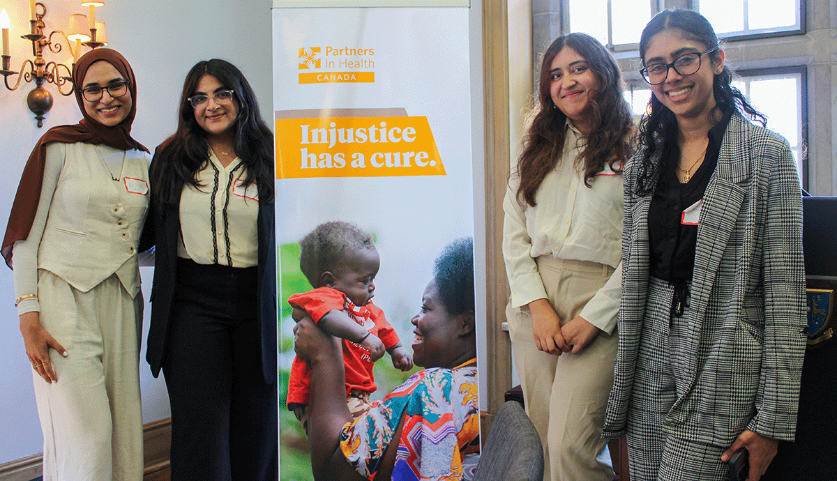 Students with McMaster University stand in front of a banner for the Partner in Health policy competition.