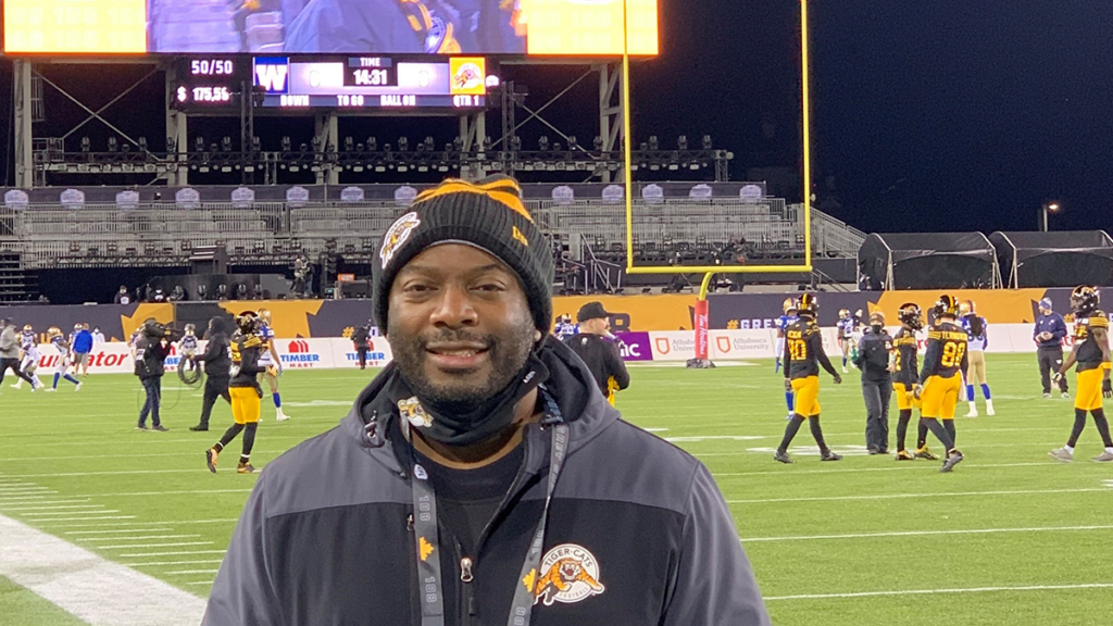 Femi Ayeni stands on the field at the Grey Cup