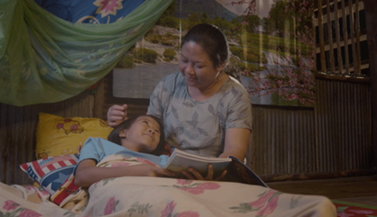 A woman can be seen reading to her child in a still from the “Being Family” film.