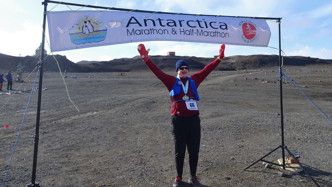 Mark Walton holds his hands up in the air after completing his marathon run on Antarctica.