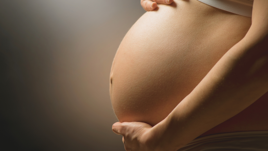 A pregnant woman holds her belly.